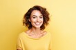Portrait of beautiful young happy smiling woman, over yellow background.