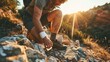Hiker applying a bandage to an injured knee on a mountain trail at sunset. Outdoor adventure and health concept for fitness and hiking articles