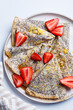 Crepes with poppy seeds, maple syrup and strawberries.