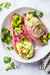 Canvas Print - Baked sweet potato halves with guacamole, edamame beans, pickled red onion and cilantro.