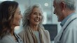 © iuricazac - Three people in a medical setting smiling and engaged in a positive interaction with a focus on the older woman's joyful expression.