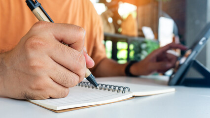 Wall Mural - businessman working at work table,home office desk background, checklist writing planning investigate enthusiastic concept. Male hand taking notes on the notepad.	