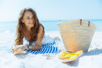 Wall Mural - happy elegant female on ocean shore with straw bag