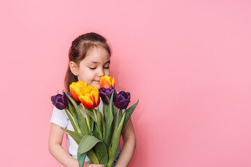 Canvas Print - Child holding a bouquet of tulips in front of a pink background.