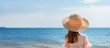 Woman in straw hat gazing at sea
