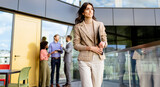 Fototapeta Las - Businesswoman Leads a Confident Stride in Modern Office Environment During a Sunny Afternoon