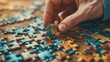 Person's hand strategically inserting a multicolored puzzle piece into jigsaw puzzle