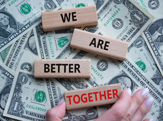 We are better together symbol. Wooden blocks with words We are better together. Beautiful dollar background. Businessman hand. We are better together concept. Copy space.