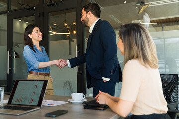 Wall Mural - Businessman and woman shaking hands in a meeting room