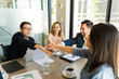 © AntonioDiaz - Inclusive group of businesspeople bringing hands together in the center during a business meeting
