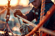 Focused Sailor Expertly Adjusting Ropes at Sunset - Nautical Mastery Banner