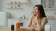 Asian ethnic dreamy woman in kitchen thoughtful chinese korean girl dreaming future think positive thoughts peaceful japanese housewife homeowner lady relax smile sit at dining table food breakfast