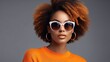 Portrait of a beautiful young Afro-American woman with curly hair and wearing sunglasses on a pink background, banner for a beauty salon or cosmetology, optics salon