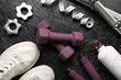 Dumbbells, shoes and measuring tape and clamps on black background