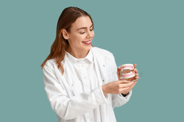 Wall Mural - Female dentist with jaw model and dental mirror on blue background. World Dentist Day