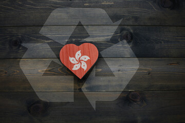 wooden heart with national flag of hong kong near reduce, reuse and recycle sing on the wooden background. concept