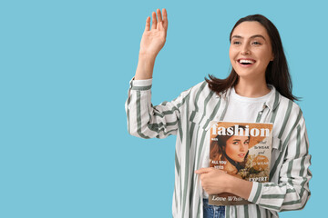 Poster - Young woman with fashion magazine waving hand on blue background