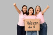 Portrait of beautiful women holding cardboard with text WE CAN DO IT on grey background