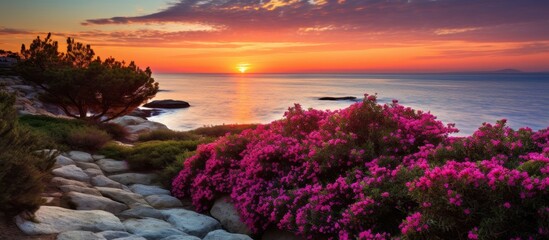 Sticker - A magenta sunset over the ocean with purple flowers in the foreground, creating a stunning natural landscape against the fluid sky and horizon