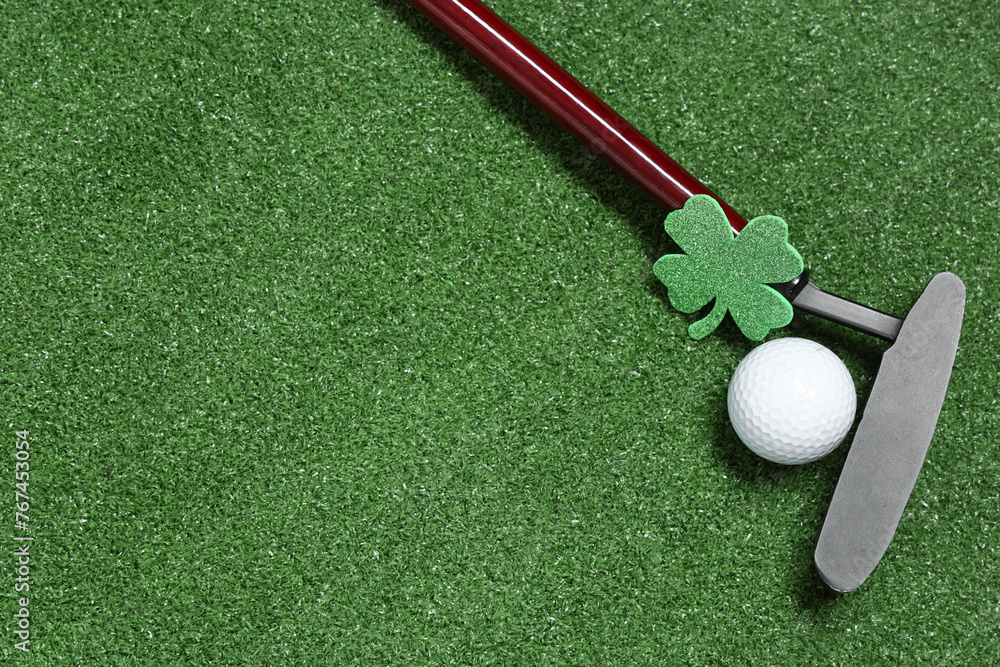 Golf club, ball and clover on green grass background. St. Patrick's Day celebration