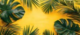 Fototapeta Mapy - Tropical palm leaves on a yellow backdrop convey a summer theme. Displayed in a flat lay style with a top-down view and space for text.