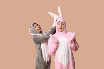 Wall Mural - Beautiful young couple in bunny costume on brown background. Easter celebration