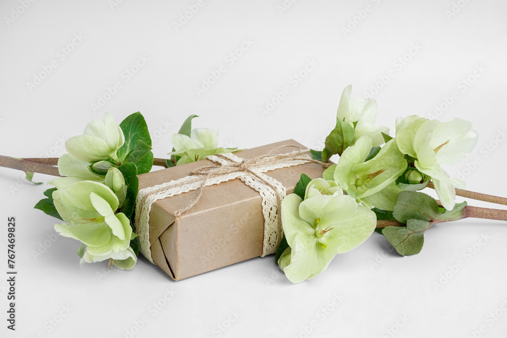 Gift box and branches with beautiful flowers on white background