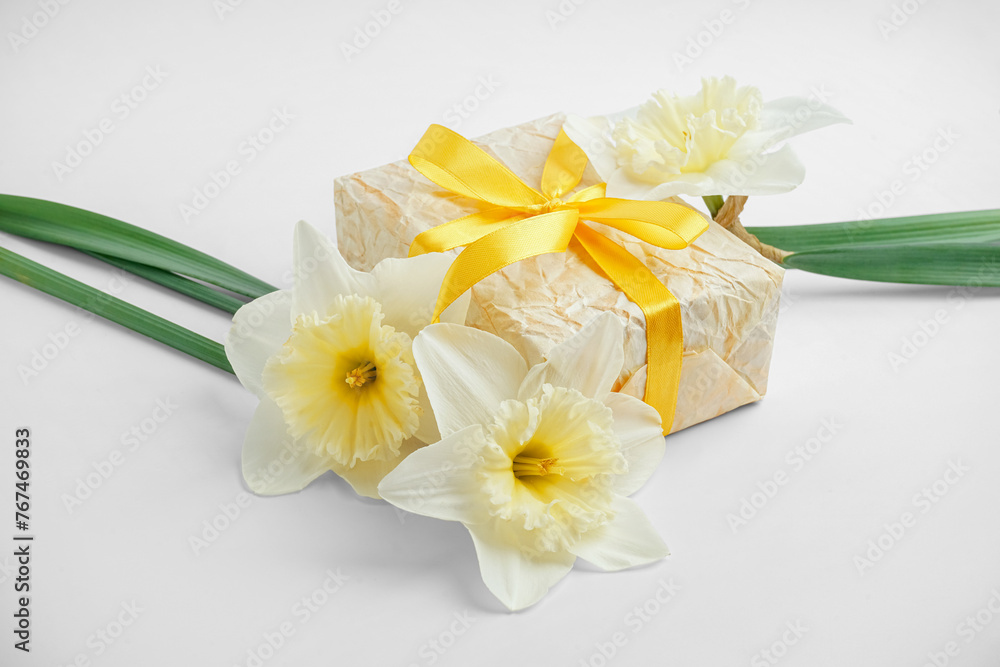 Gift box with daffodil flowers on white background