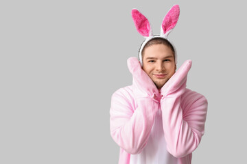 Canvas Print - Young man in bunny costume on grey background. Easter celebration