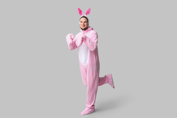 Wall Mural - Young man in bunny costume on grey background. Easter celebration