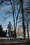Fototapeta  - Active lifestyle concept with smiling woman enjoying a bike ride in a park.