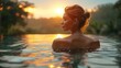 A woman is happily swimming in the liquid of a pool at sunset, surrounded by a natural landscape with trees, plants, and the sun lighting up the sky