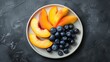  a white plate with blueberries, peaches, and peaches on a black tablecloth with a gray background.