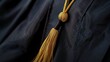 A black graduation gown with a gold tassel and a master's degree hood, signifying advanced achievement