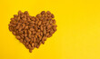Close-up peeled almonds nuts heart yellow background top view using for your advertising