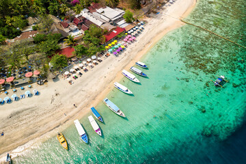 Wall Mural - Birds eye view of colorful sun umbrellas and boats on a small, warm tropical beach