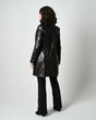 Full length portrait of brunette woman wearing long leather trench coat and black boots. Standing pose walking away from camera, facing backwards. Isolated silhouette on white studio background.