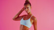 Fit female model in sportswear on a pink background, athletic and confident.