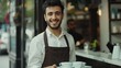 Cheerful male waiter carrying coffee cups on tray and smiling at camera, working in his small business restaurant cafe. copy space for text.