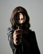 close up portrait of beautiful brunette woman wearing black leather trench coat. Holding detective magnifying glass, reaching out towards camera, searching for discovery. Isolated  studio background