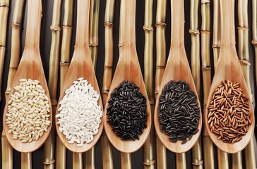 Wall Mural - A collection of different colored rice grains are displayed on a wooden table