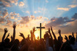 crowd of worshippers with hands raised to praise to a giant cross backlit by sunrise