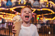 © Cavan Images - Young smiling boy holding an ice cream cone with ferris wheel