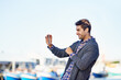 © Mapodile M/peopleimages.com - Man, smartphone and photography at harbor, outdoor and smile by ocean with creativity for web blog. Person, photographer and phone for profile picture, social media or memory by sea port in Cape Town