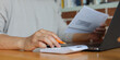 © chinnarach - close up young man hand press on calculator and open over group of invoice letter mail from bank after pass due date of payment for money and debt management concept