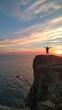 © Image-Love - A person is standing on a cliff overlooking the ocean. The sky is a beautiful mix of pink and orange hues, creating a serene and peaceful atmosphere. The person appears to be enjoying the view