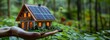 Person holding miniature house with solar panels, promoting green energy