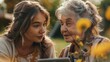 Young girl showing someting on tablet to elderly grandmother at garden party. Love and closeness between grandparent and grandchild.
