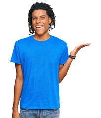 Wall Mural - Young african american man wearing casual clothes smiling cheerful presenting and pointing with palm of hand looking at the camera.
