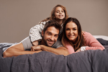 Poster - Parents, child and portrait in bedroom to relax in home for weekend break, family time and happiness for bonding. Father, mother and girl comfy or cozy together for love, care and safety or security.